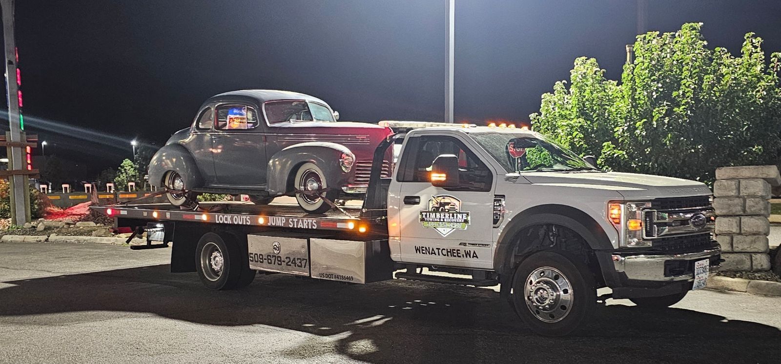 A tow truck is carrying a car on the back of it.