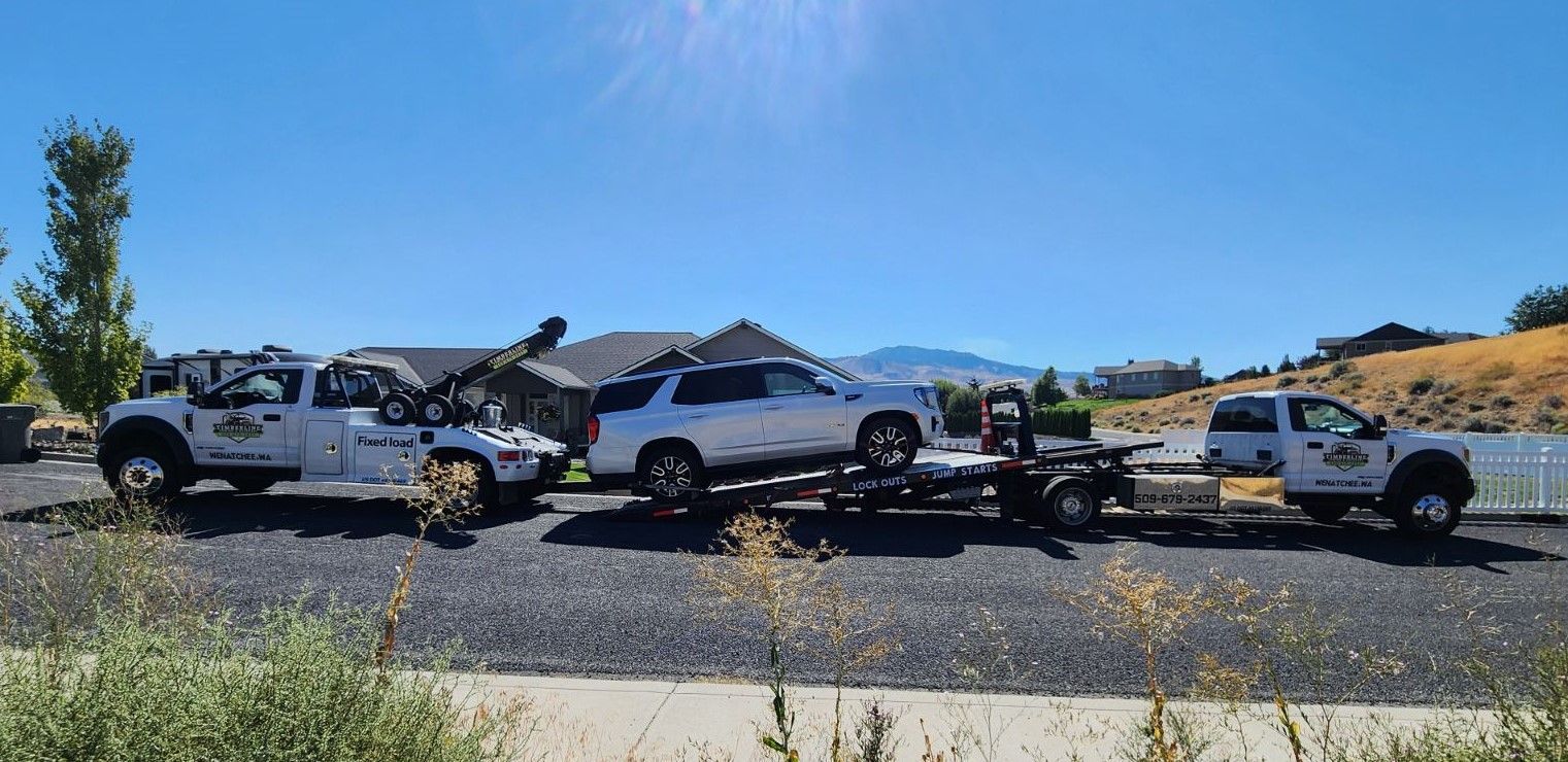 A tow truck is carrying two cars on a trailer.