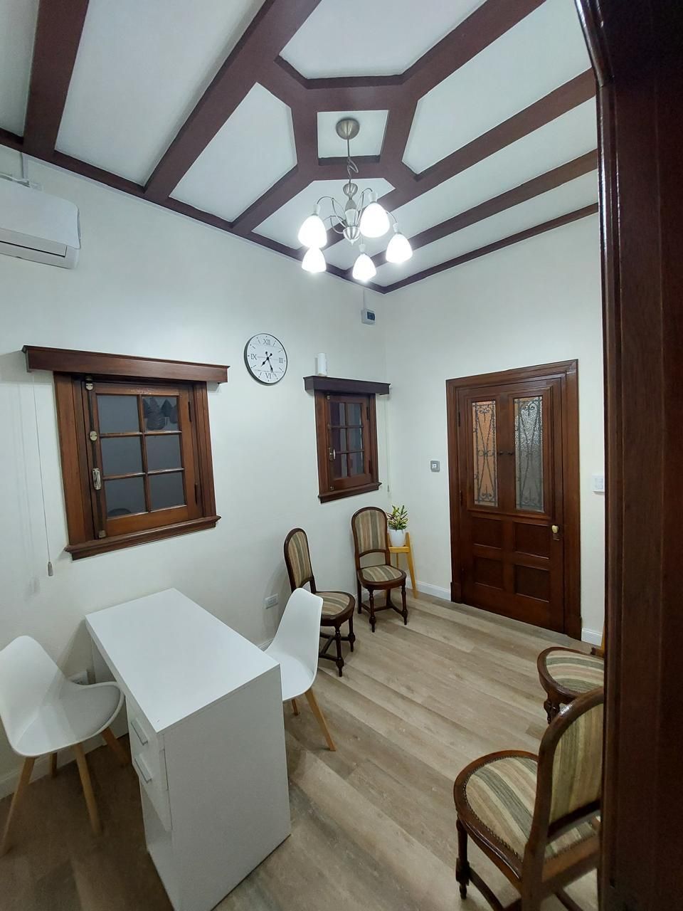 Una habitación con un escritorio y sillas y un reloj en la pared.