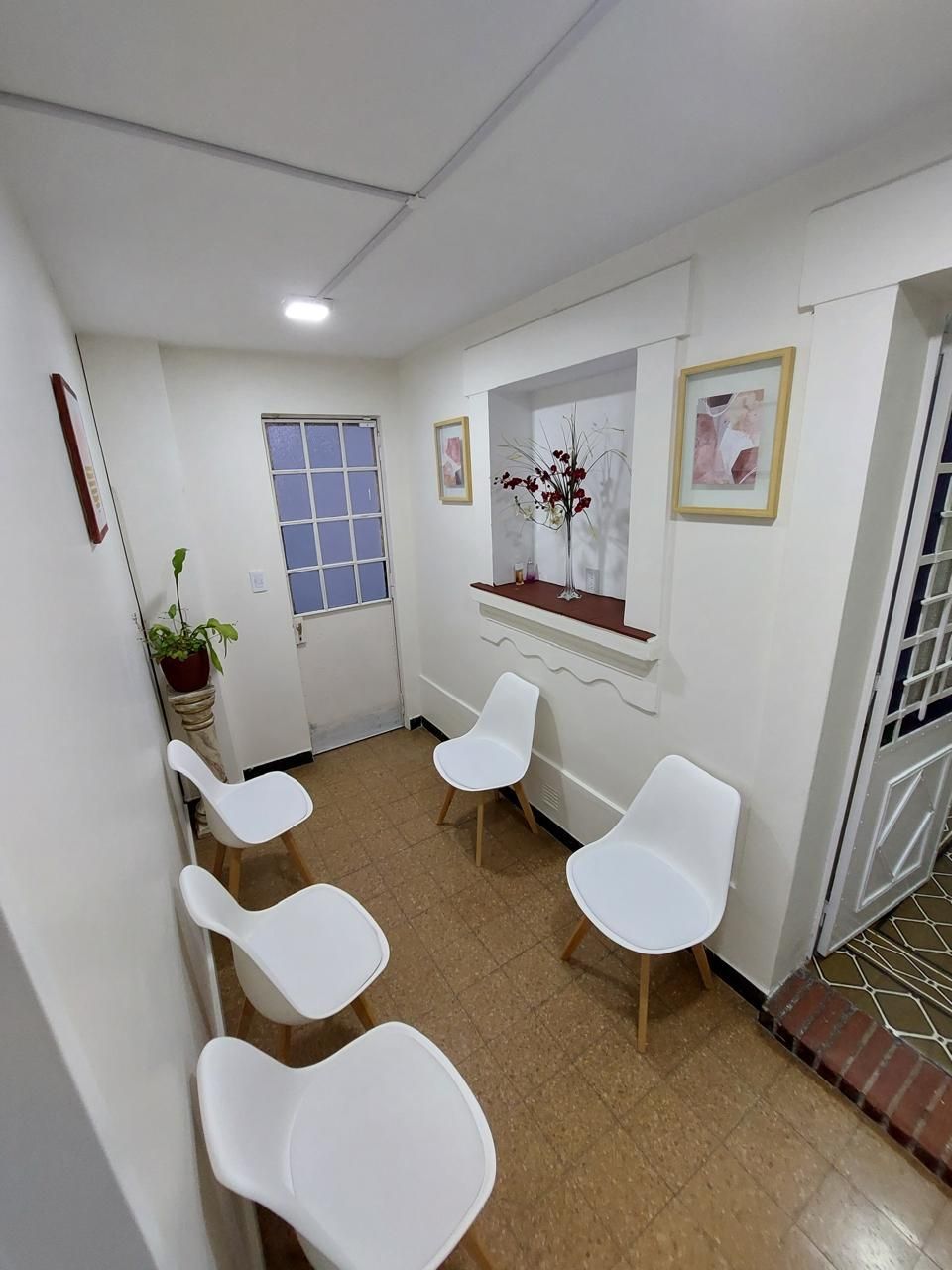 Una sala de espera con sillas blancas y una ventana.