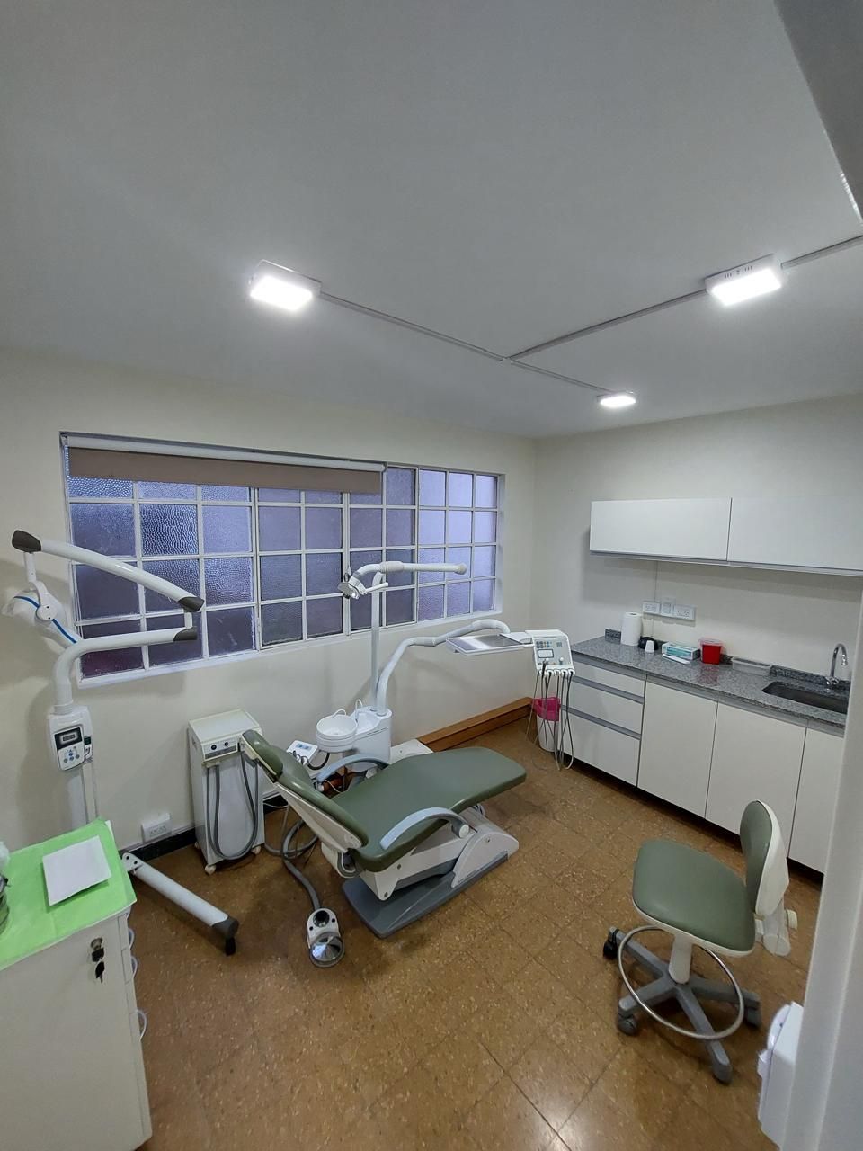 Un consultorio dental con un sillón dental y un lavabo.