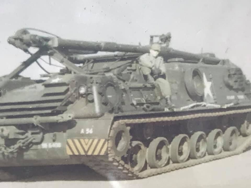 A black and white photo of a man sitting on a tank