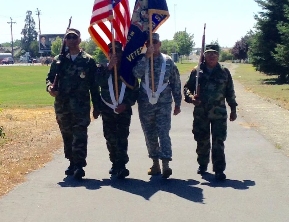 A group of soldiers carrying a flag that says veteran