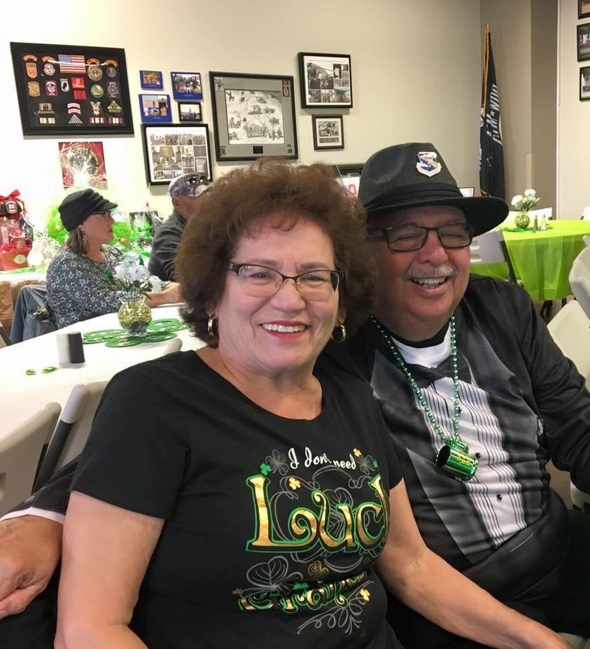 A man and a woman are sitting at a table and the woman is wearing a shirt that says loud