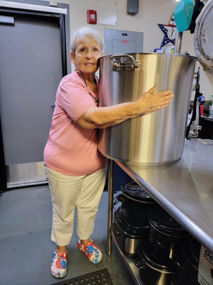 A woman is holding a large pot in a kitchen.