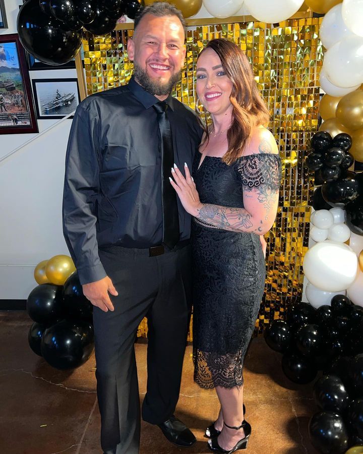 A man and a woman are posing for a picture in front of balloons.