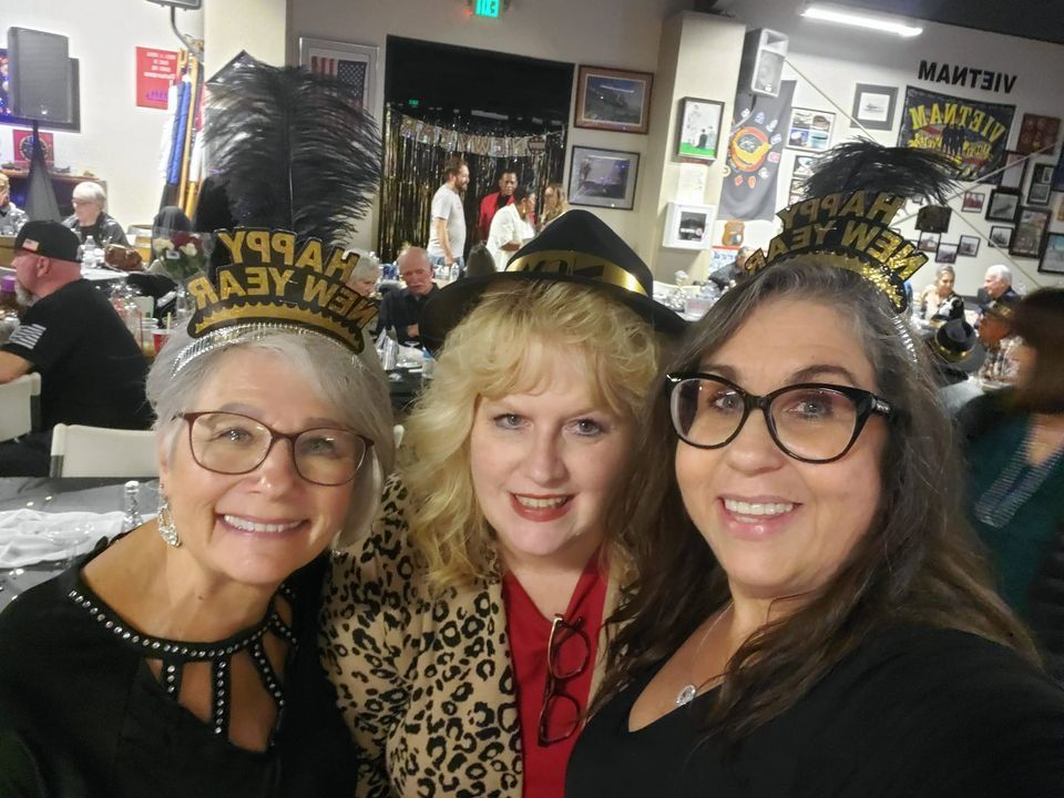 Three women wearing new year 's eve hats pose for a picture
