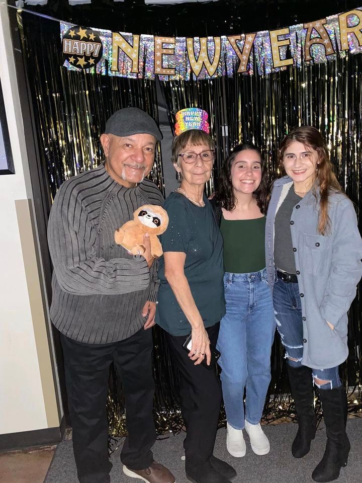 A family is posing for a picture in front of a new year 's eve banner.