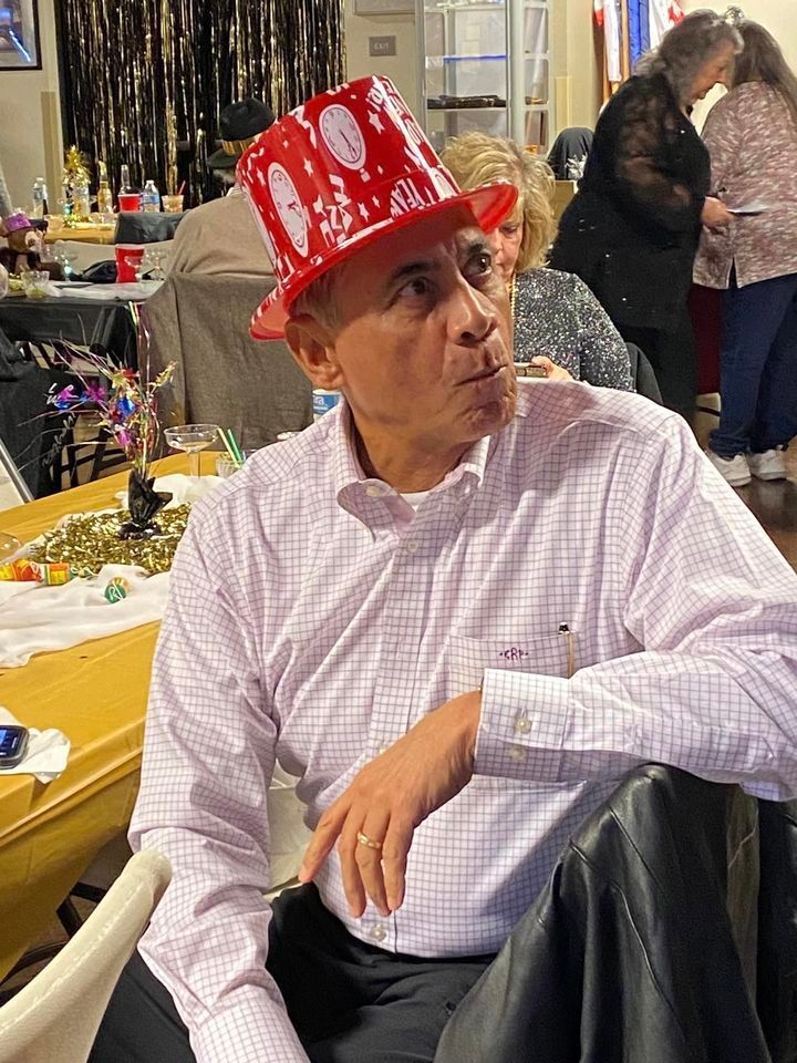 A man wearing a red top hat is sitting at a table.