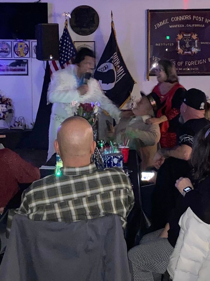 A man is singing into a microphone in front of a crowd of people.