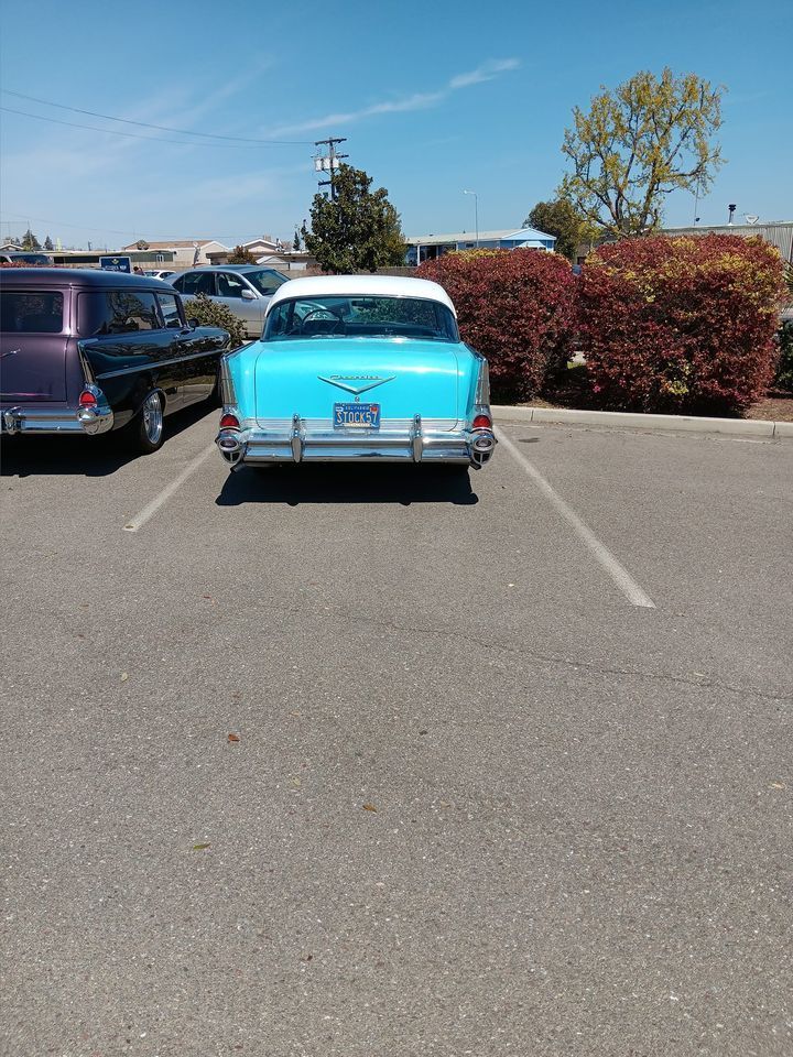 A blue car is parked in a parking lot with other cars.