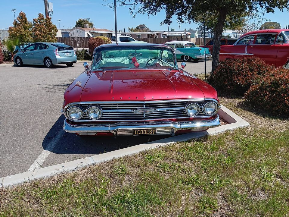 A red car is parked in a parking lot with a license plate that says acorn