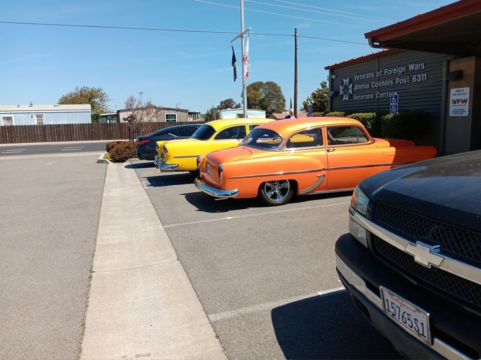 A row of old cars are parked in a parking lot