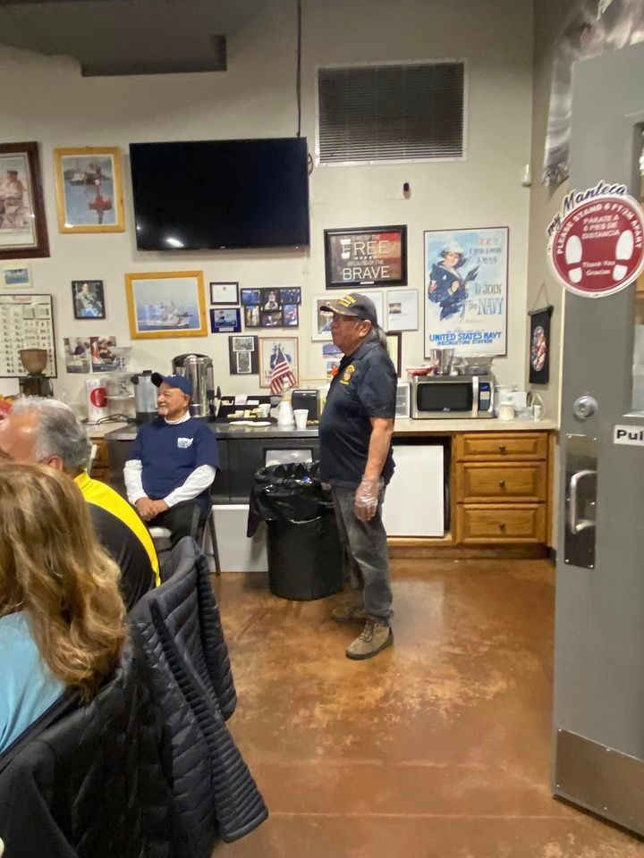 A man is standing in front of a group of people in a room.