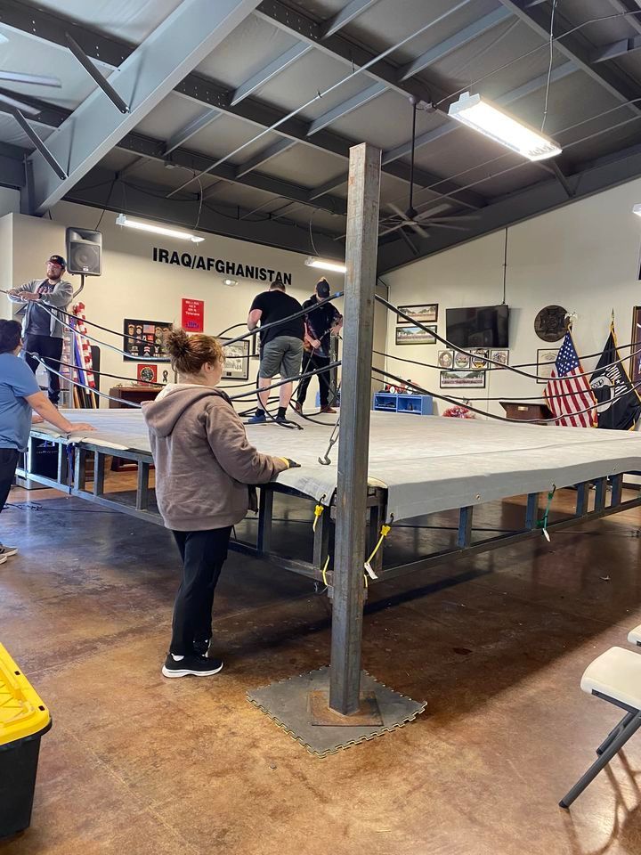 A woman is standing on a stage in front of a boxing ring.