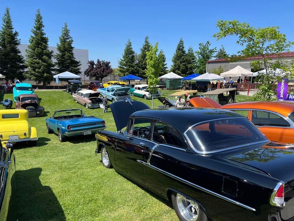 A row of old cars are parked in a grassy field.