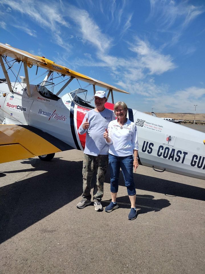 A man and a woman are standing in front of a us coast guard plane.