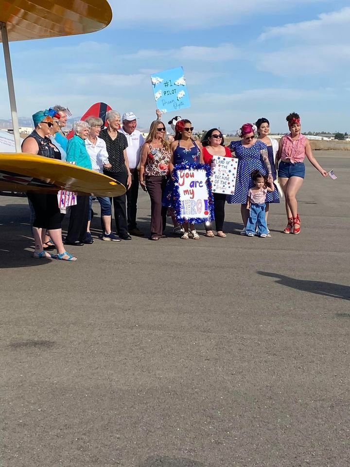 A group of people standing in front of a plane holding signs