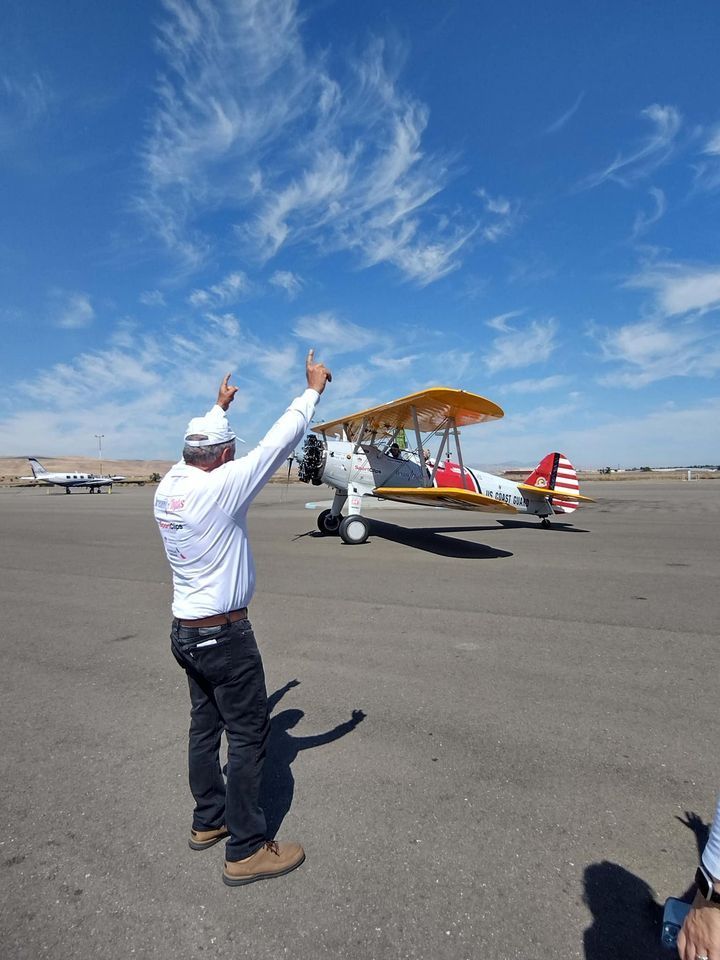 A man is standing in front of a small plane on a runway.