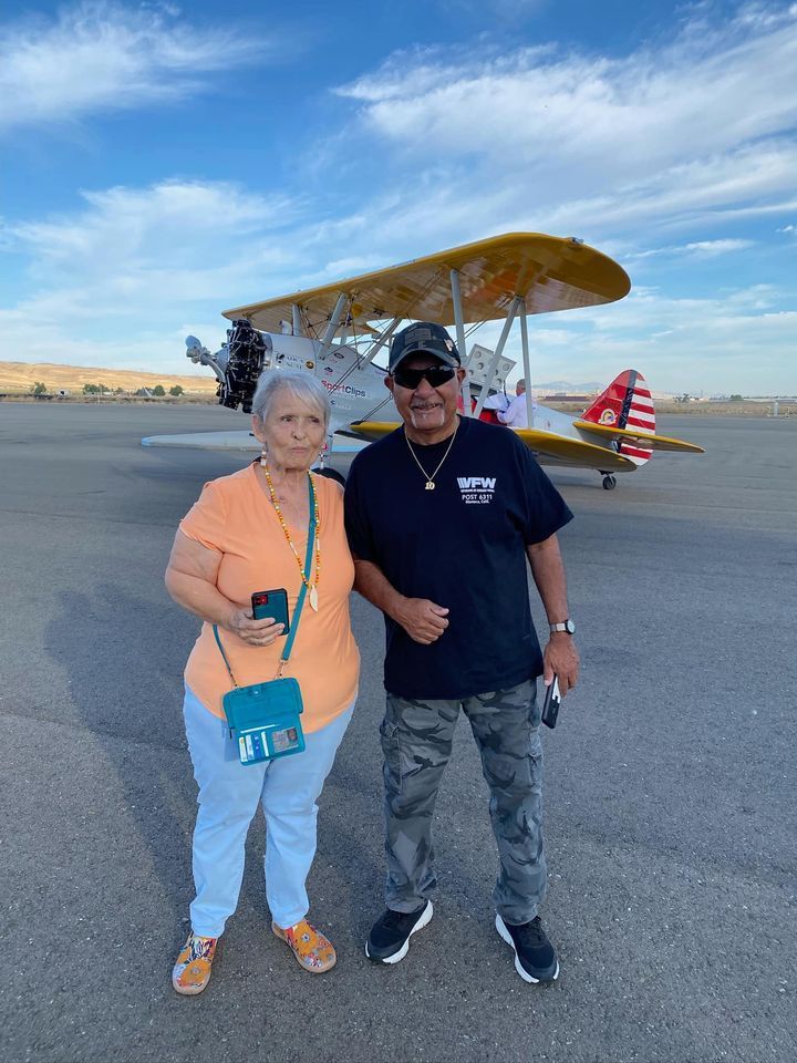 A man and a woman are standing in front of an airplane.