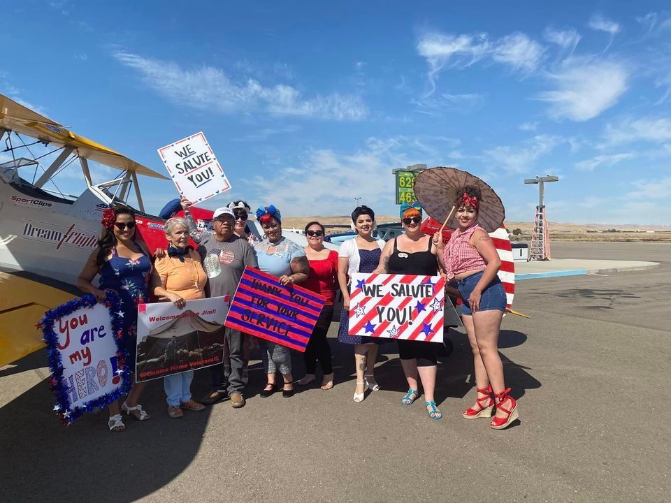 A group of people are standing in front of a plane holding signs.