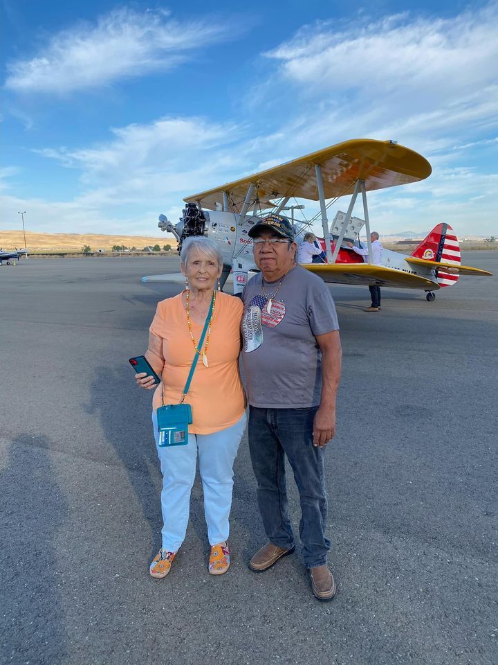 A man and a woman are standing in front of a plane.