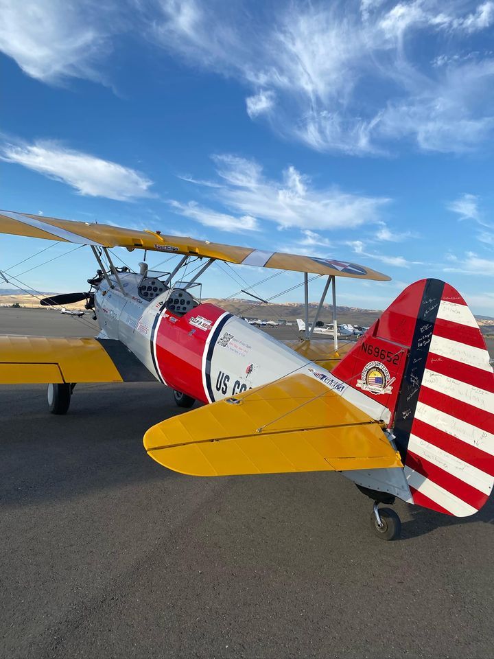 A red , white and yellow plane is parked on a runway.
