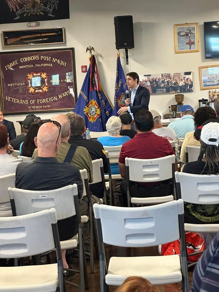 A man is giving a speech to a group of people sitting in chairs.
