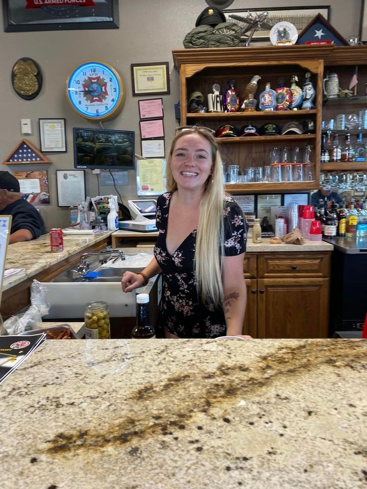 A woman is standing behind a counter in a restaurant.