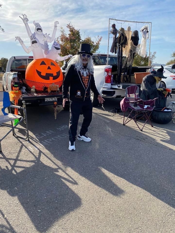 A man dressed as a skeleton is standing in a parking lot.