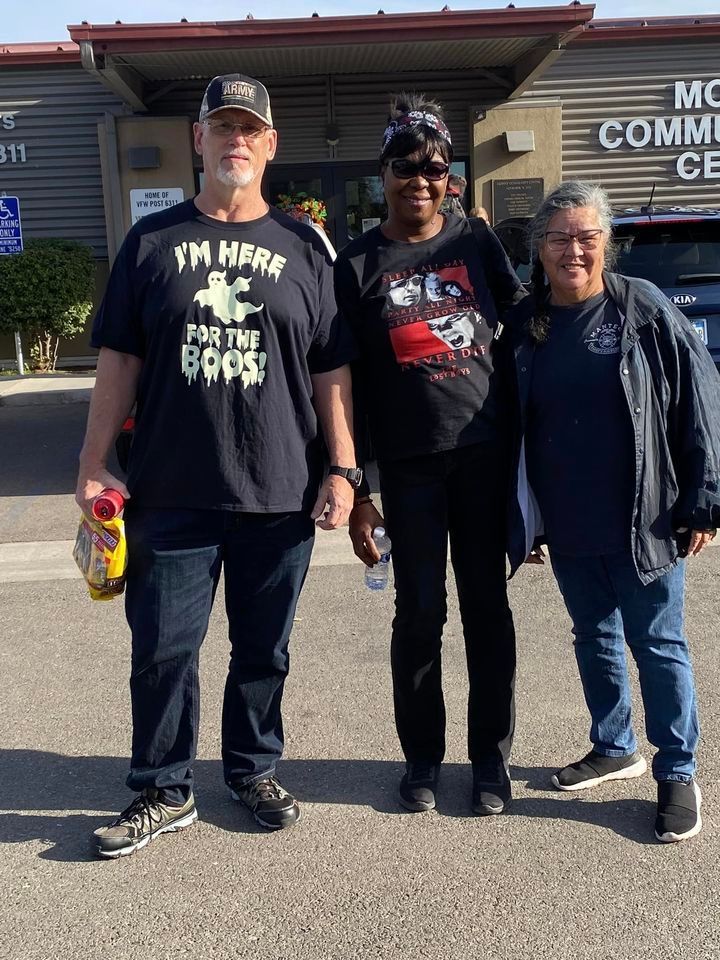 A man and two women are posing for a picture in front of a building.