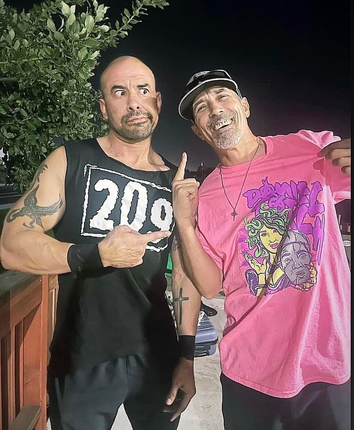 Two men standing next to each other one wearing a pink shirt with the number 209 on it