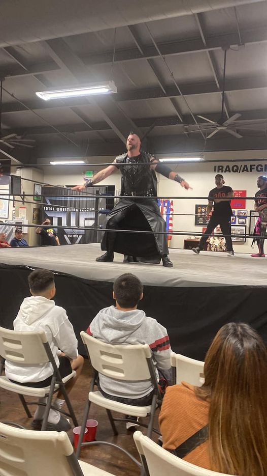 A group of people are watching a wrestling match in a ring.