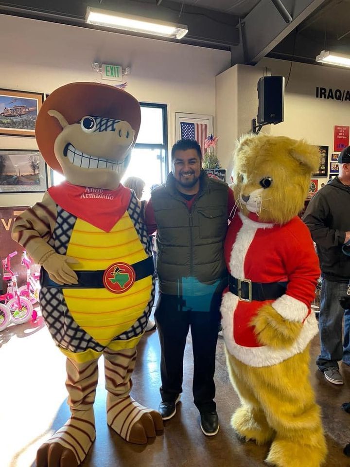 A man is posing for a picture with two mascots