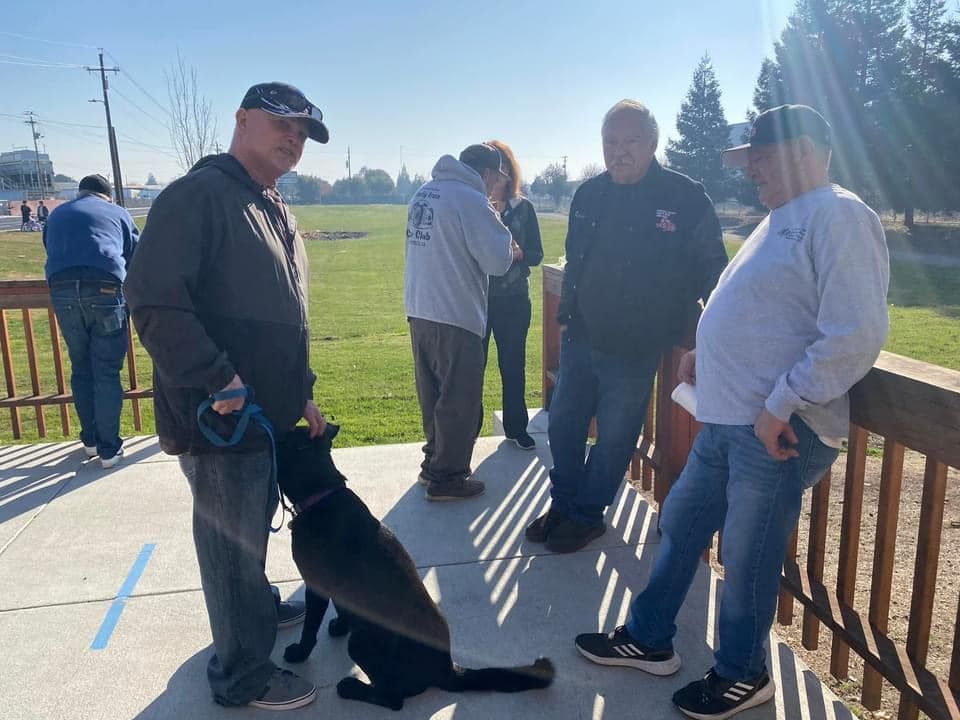A group of men are standing around a dog on a sidewalk.