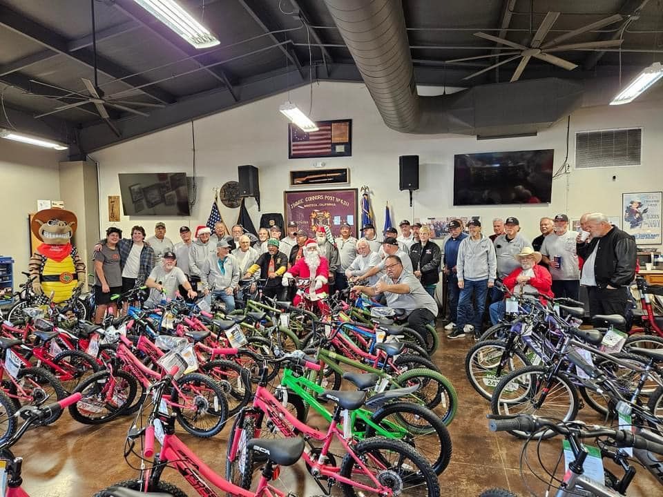 A group of people are standing in a room filled with lots of bicycles.
