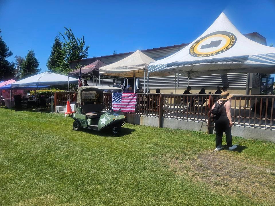 A golf cart is parked in the grass in front of a tent.
