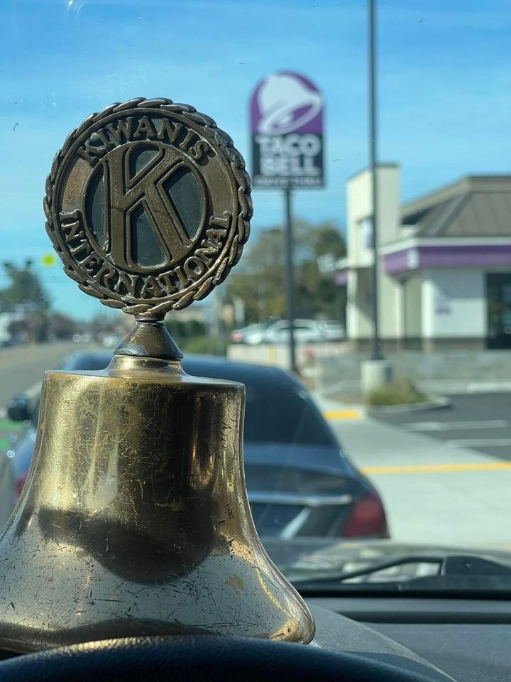 A taco bell sign is behind a brass bell