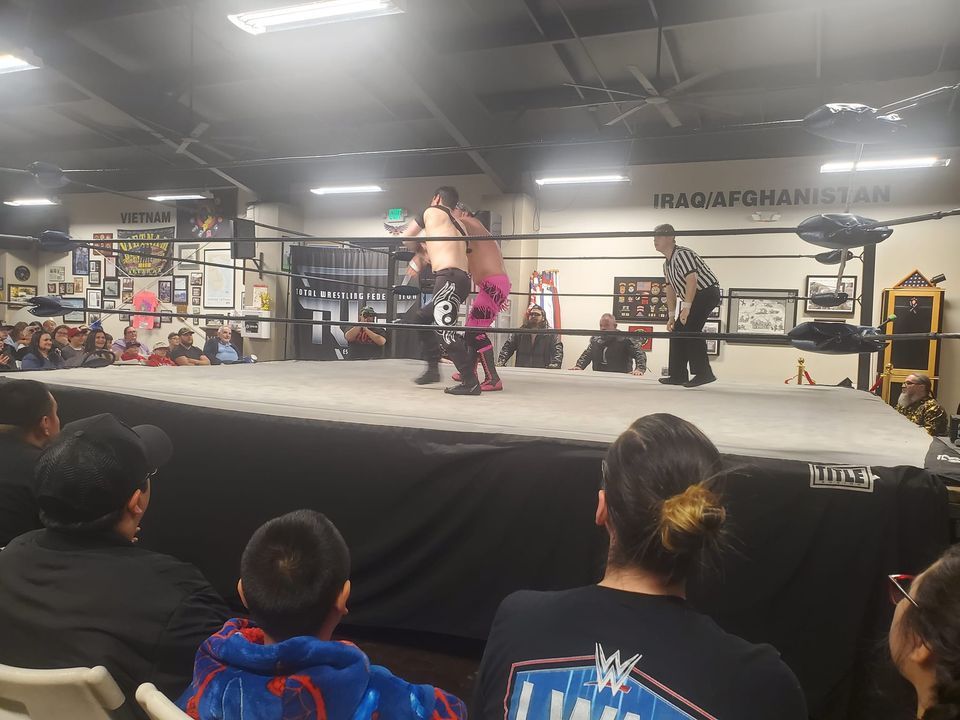 A group of people are watching a wrestling match in a ring