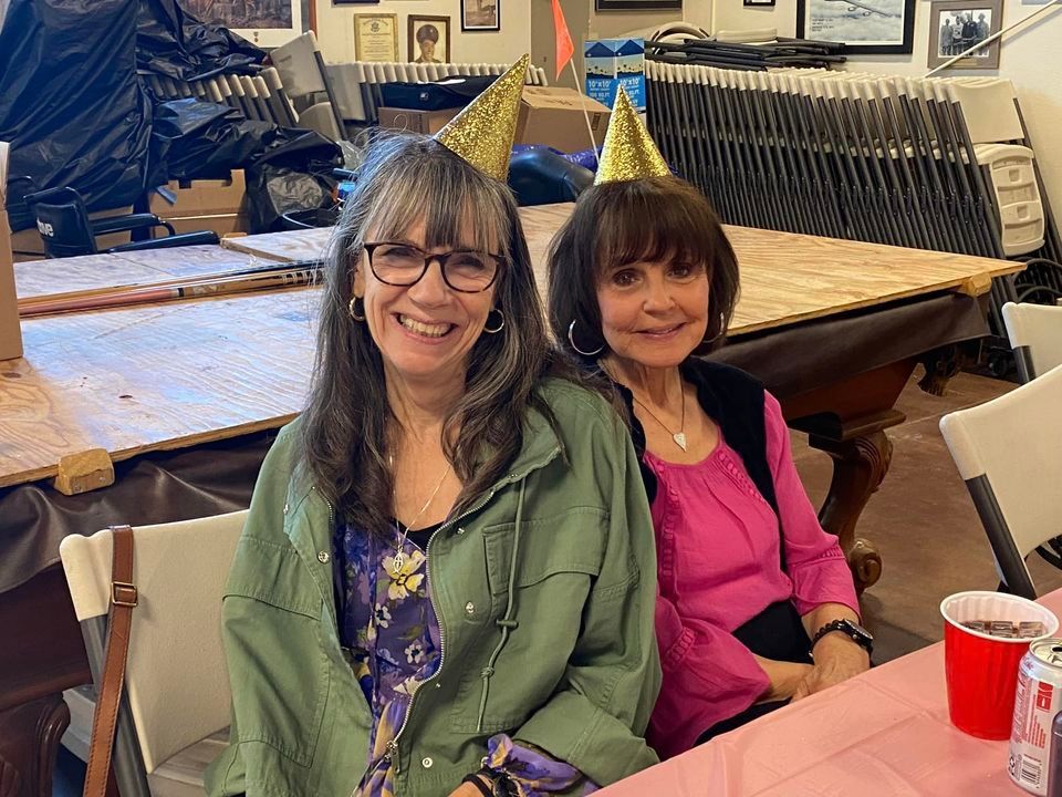 Two women wearing party hats are sitting at a table.