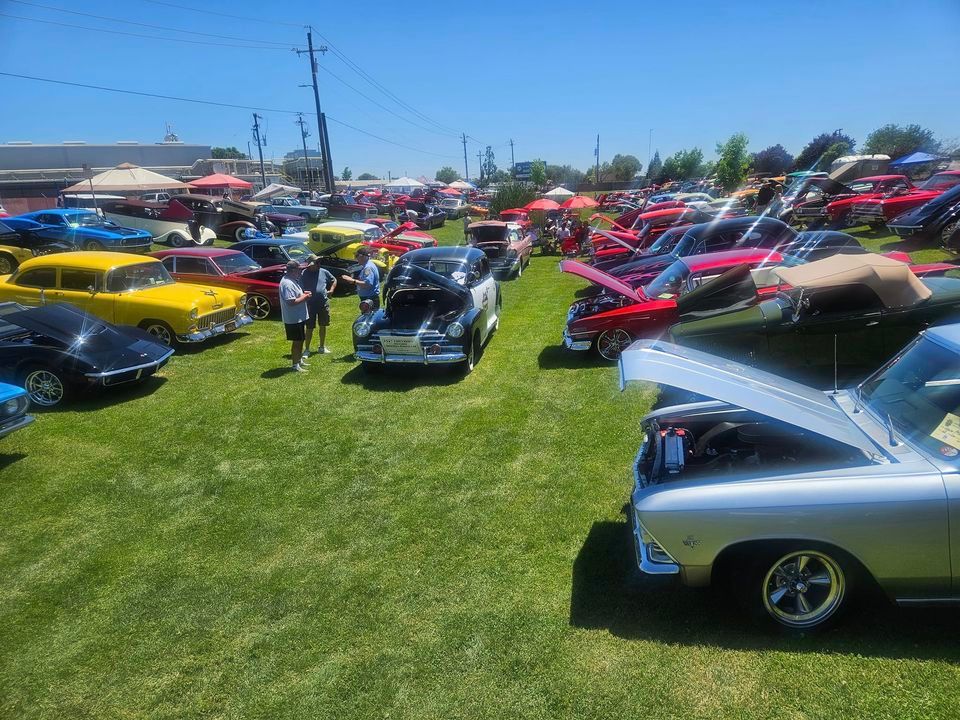 A lot of cars are parked in a grassy field at a car show.