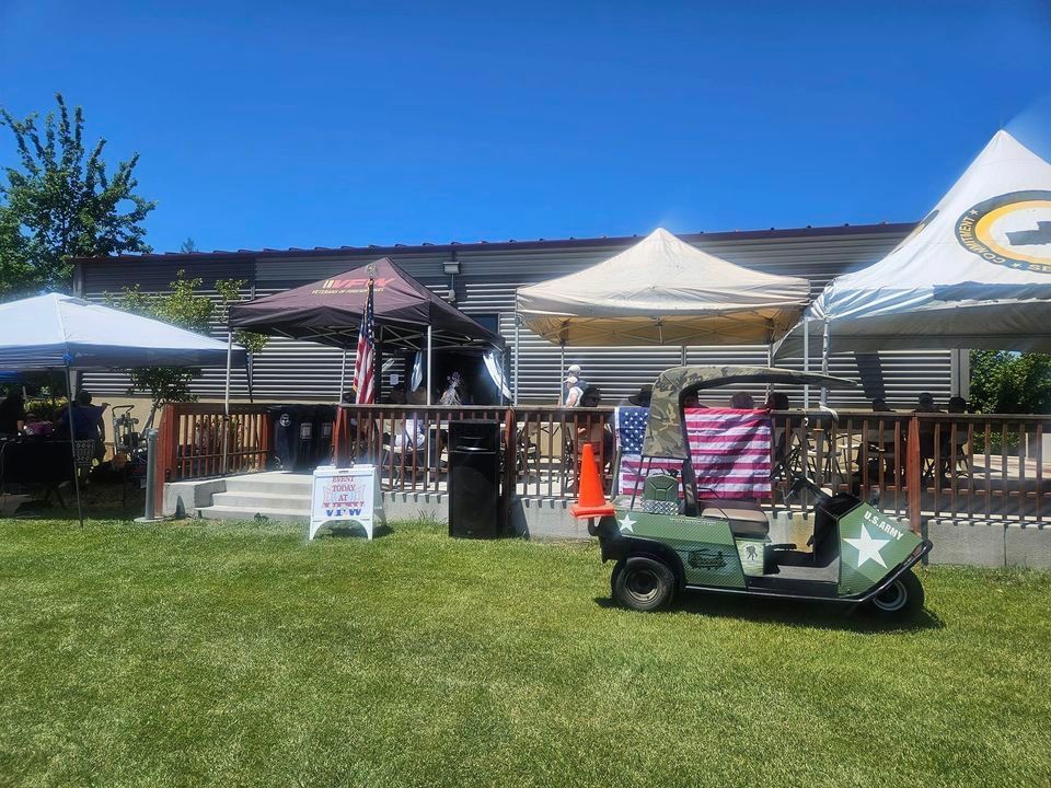A golf cart is parked in the grass in front of a building.