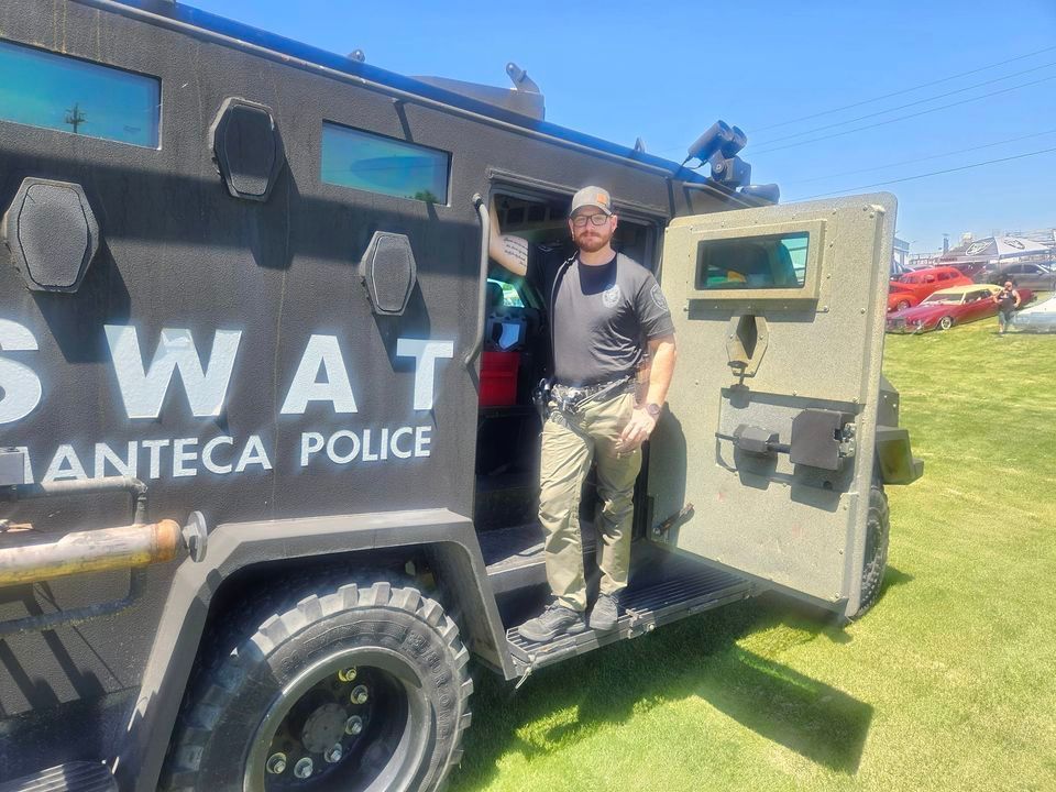 A man is standing next to a swat vehicle.