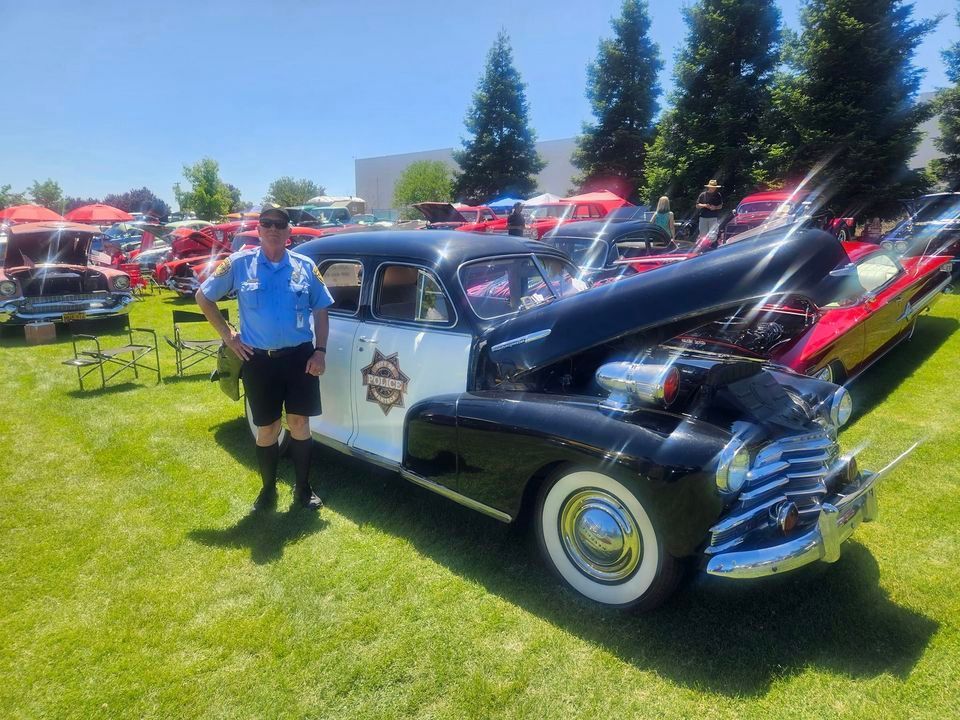 A man is standing next to an old police car