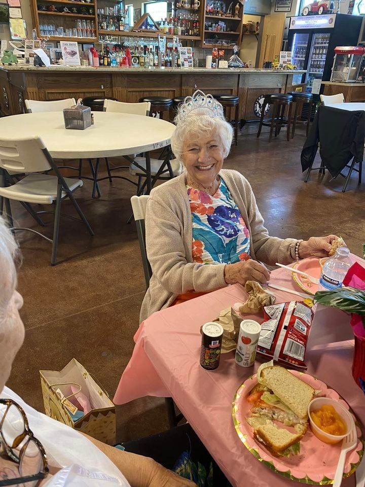 A woman is sitting at a table with a sandwich on it.