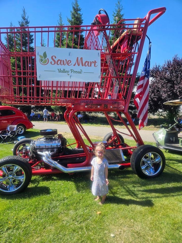 A little girl is standing in front of a giant shopping cart that says save mart