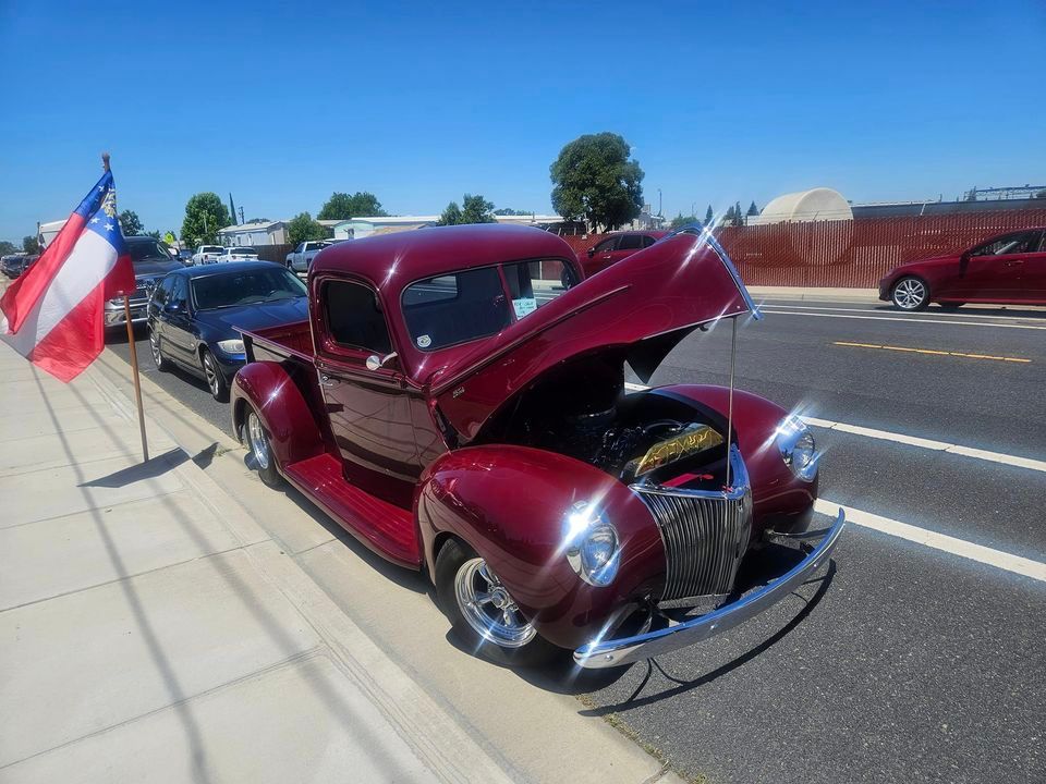 A red truck with the hood up is parked on the side of the road