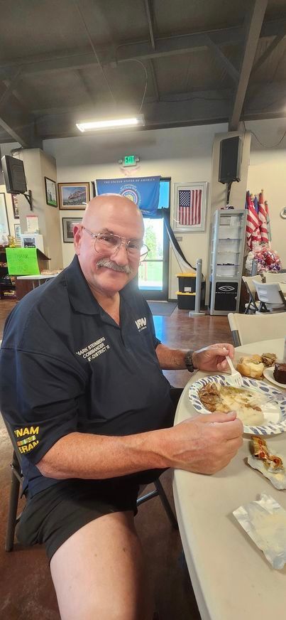 A man without pants is sitting at a table eating food.