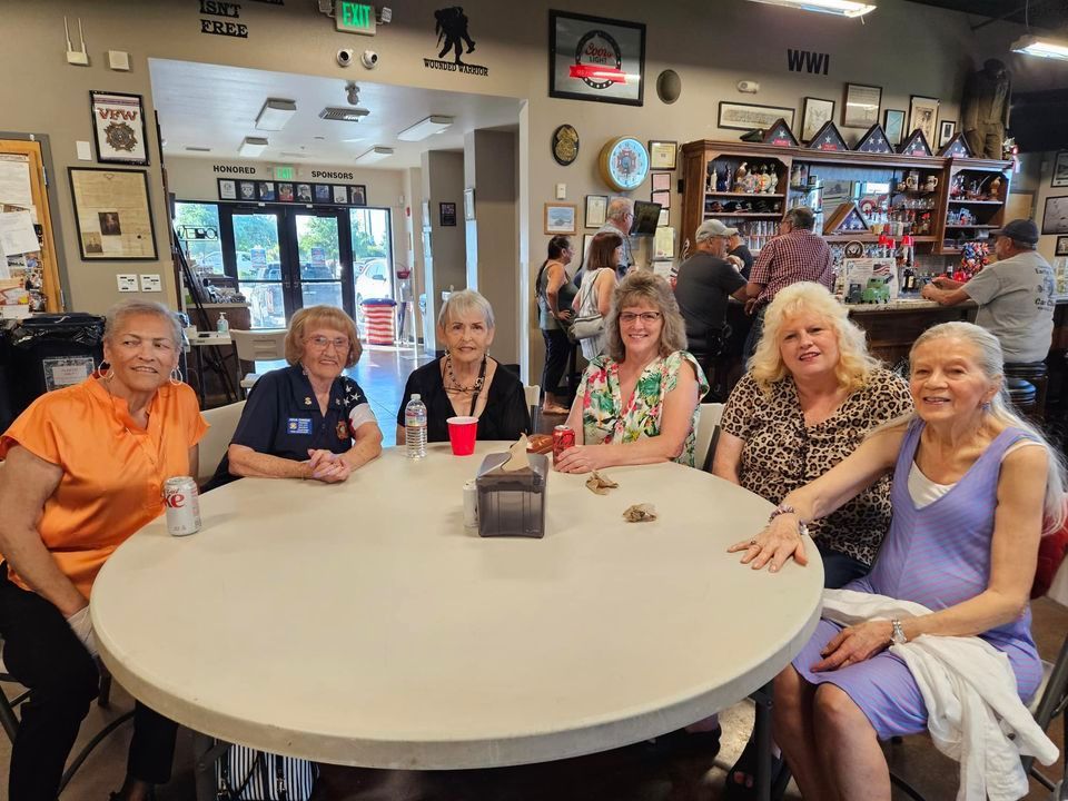 A group of women are sitting around a table in a room.