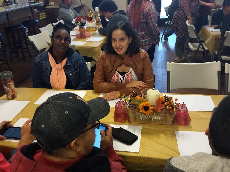 A man is taking a picture of a woman sitting at a table